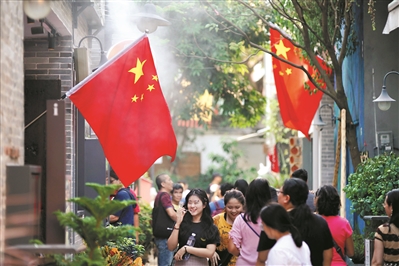 市民和游客在飘扬的国旗下逛永庆坊。