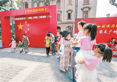 在广州的沙面等景点，不少市民游客自觉排队与国旗同框合影留念。