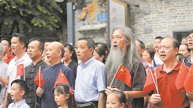 荔湾群众手持国旗唱国歌。