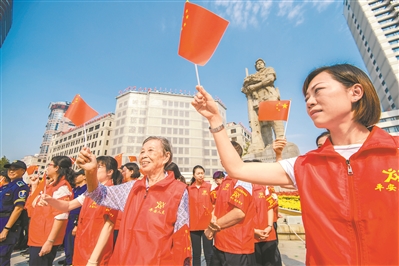 “广州街坊”队伍于广州解放纪念塑像前手持国旗欢呼。