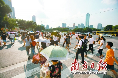 体育东路斑马线上的行人迎着烈日过马路。