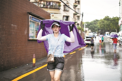 路人披防晒衣在雨中奔跑。