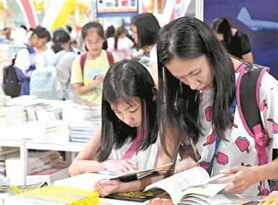 昨日，由广东省妇联主办的“书香飘万家”家庭亲子阅读主题活动在当天开幕的南国书香节举行。图为家长和孩子一起阅读和选购图书。