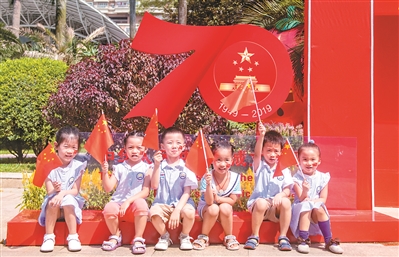 幼儿园的小朋友在“我和国旗同框”的布景前拍照。