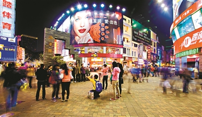 夜幕下的北京路步行街，灯光璀璨，游客在拍照“打卡”。