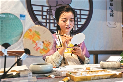 宋“潮”游乐园内有身穿汉服的姑娘在扇上画画